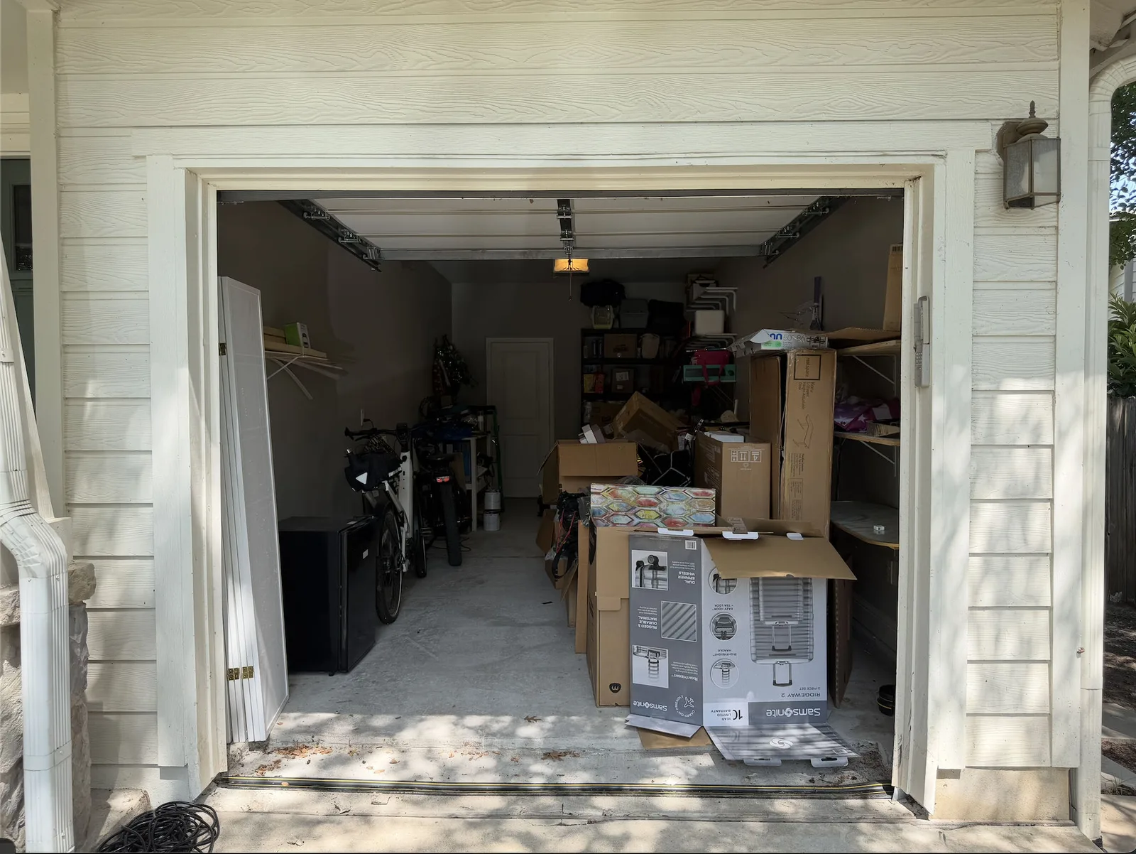Single-car garage in South Austin stacked with boxes and luggage before cleanout