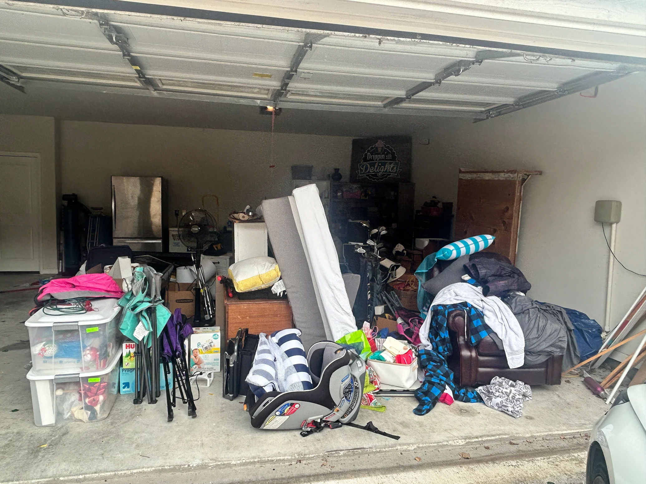 Packed garage with furniture, mattress, and household items before cleanout