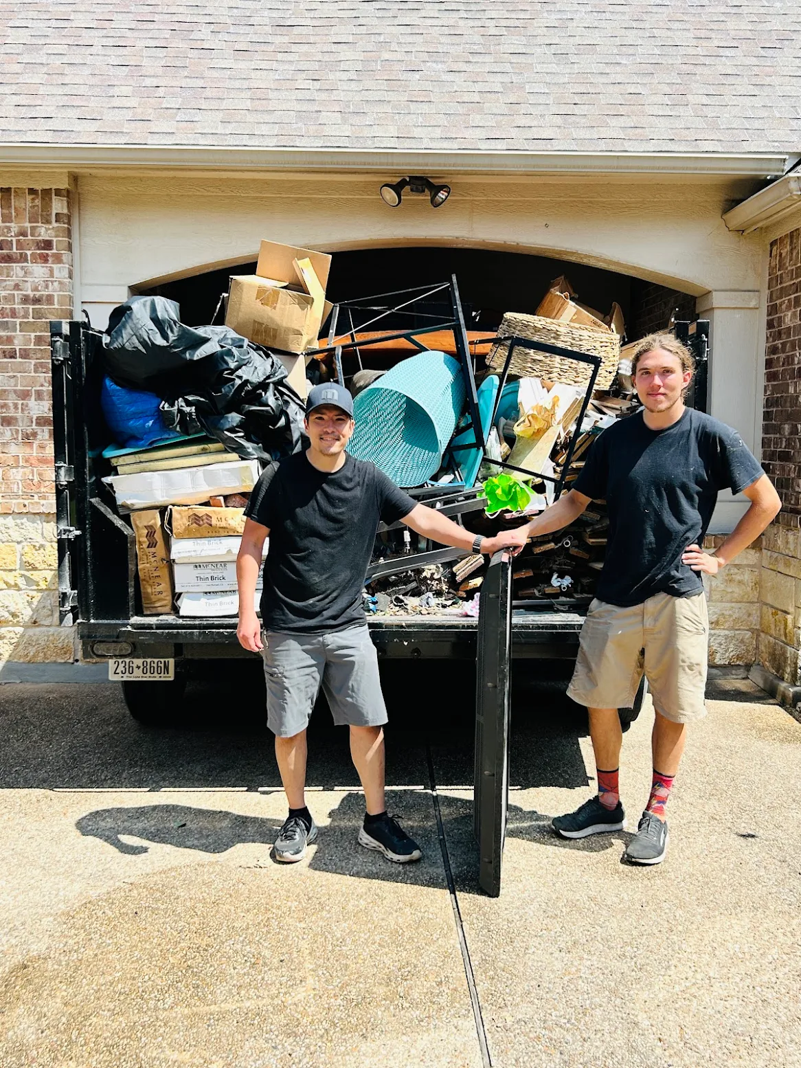 Get Your Garage Back crew standing in front of fully loaded dump trailer after garage cleanout