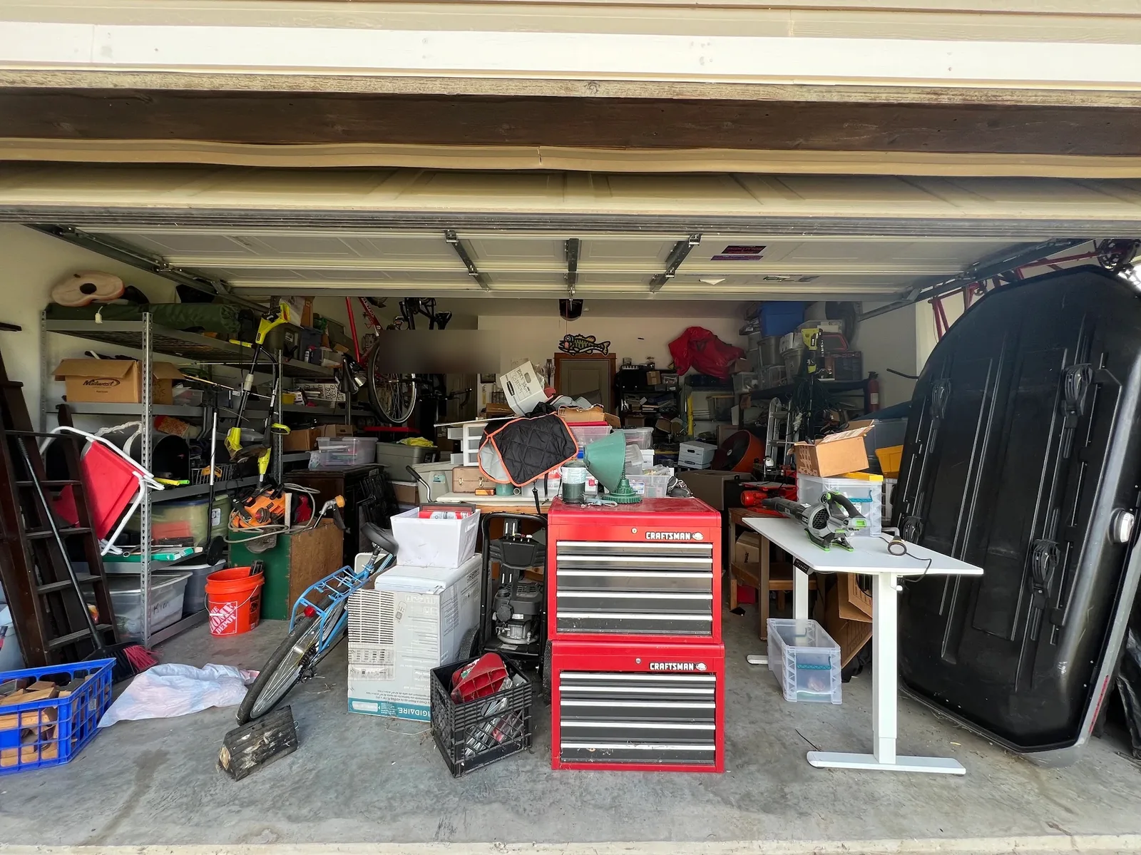 Two-car garage floor packed with tool chests, boxes, and equipment before cleanout