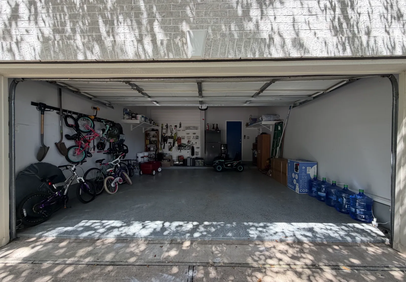 The same two-car garage with bikes hung on the wall, tools on slatwall, shelves up and the floor clear, the same day