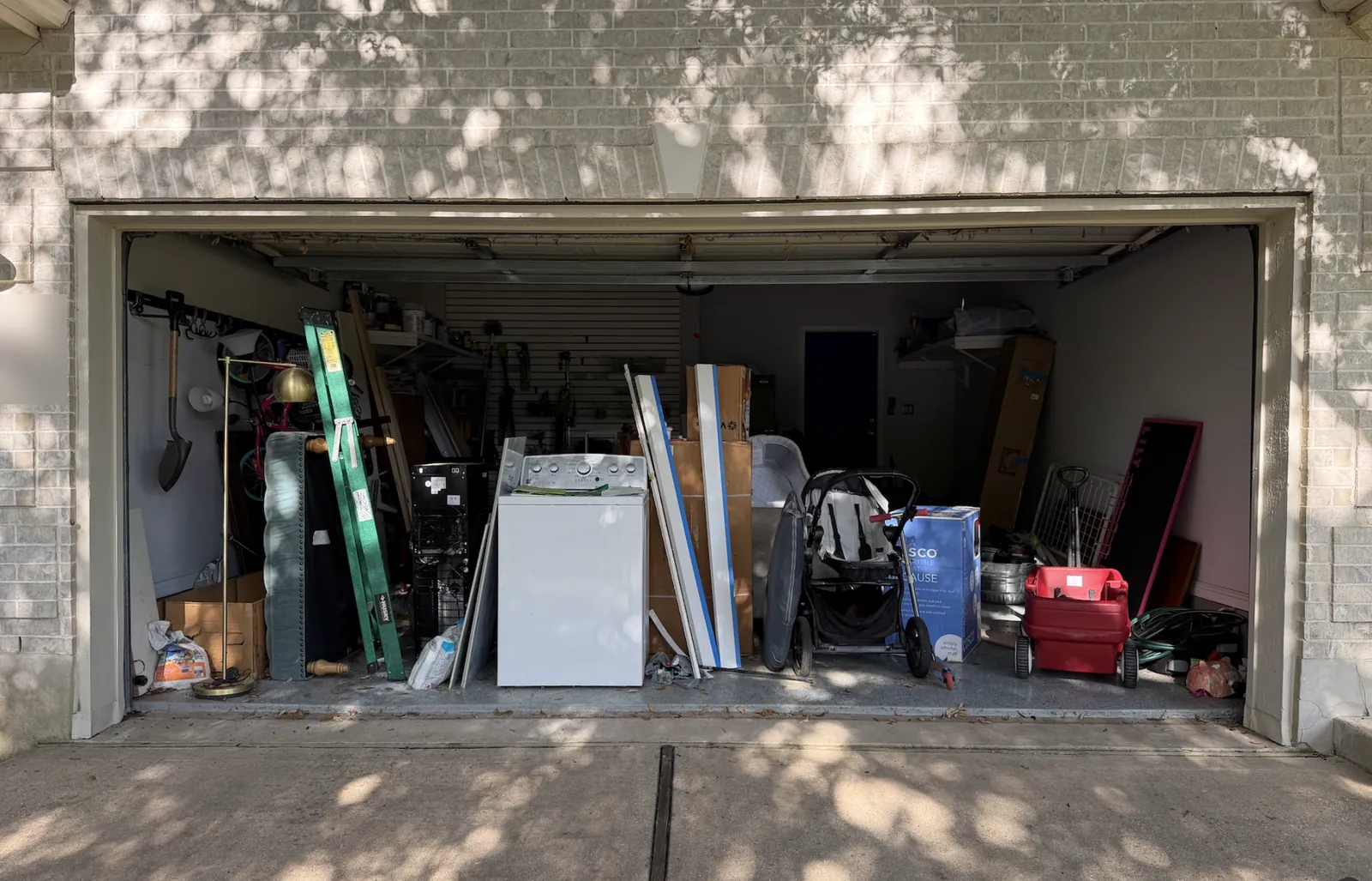 A two-car garage packed with a washer, ladder, stroller, boxes and furniture before a Get Your Garage Back cleanout